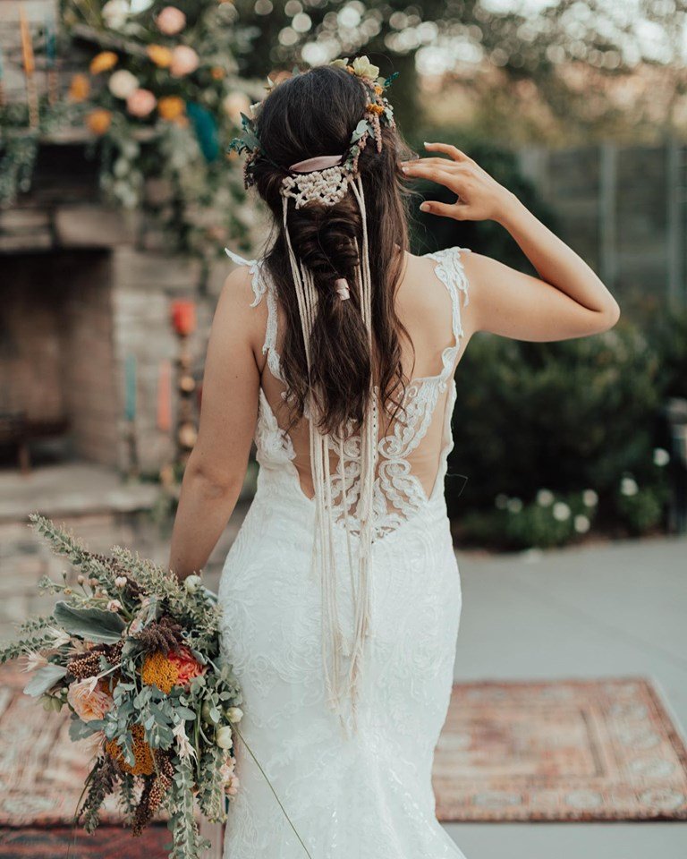 From behind, we see the details of the model's hair and dress which include macrame and lace details of this styled shoot.