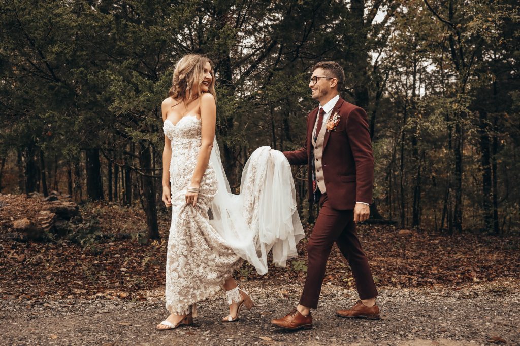 Boho Glam Bride and Groom take a stroll on their wedding day while the groom holds his bride's train.