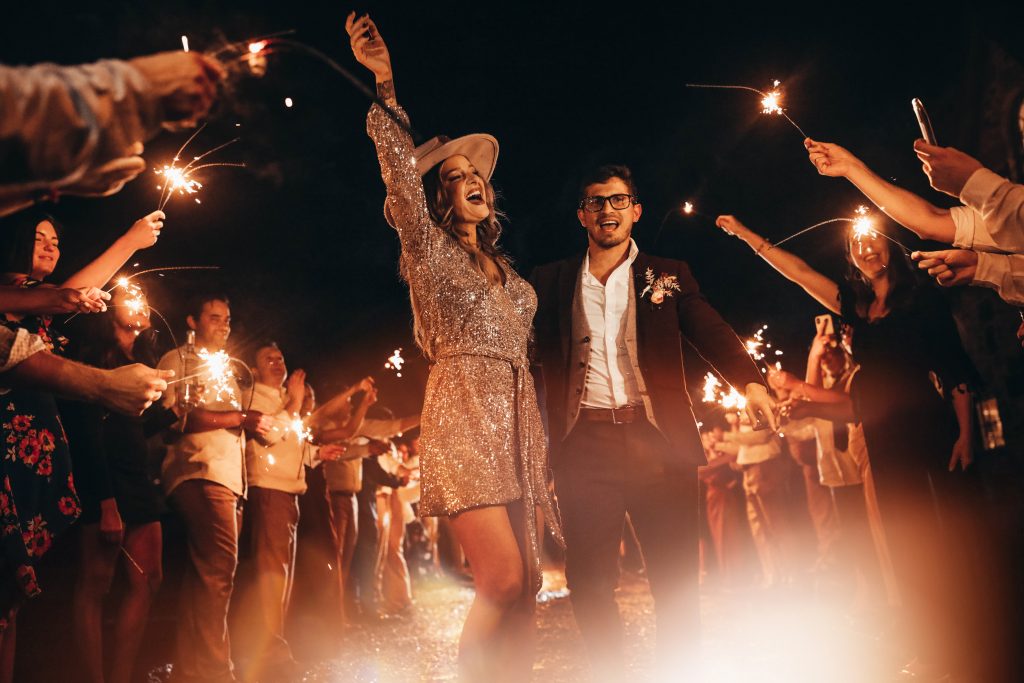 Bride and groom glow as they walk through a tunnel of sparklers with all of their friends surrounding.