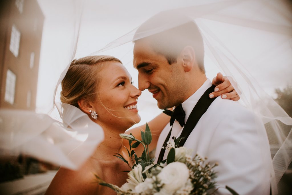 Bride and Groom snuggle under the veil at their chic industrial wedding