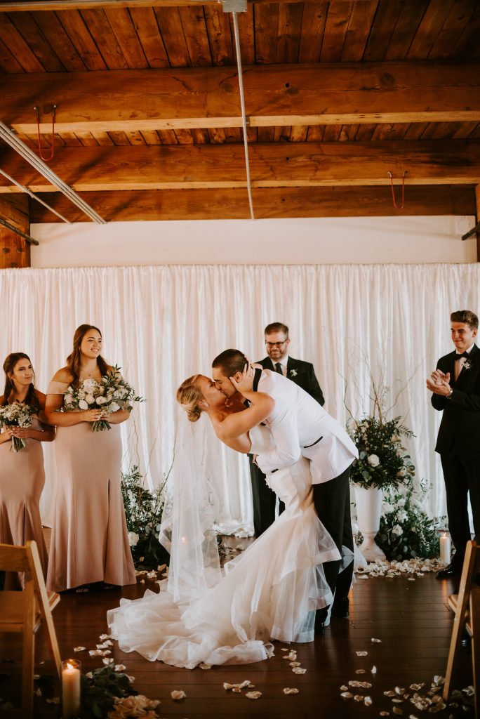 Bride and groom embrace and kiss after saying their "I Do's" at their industrial chic wedding.